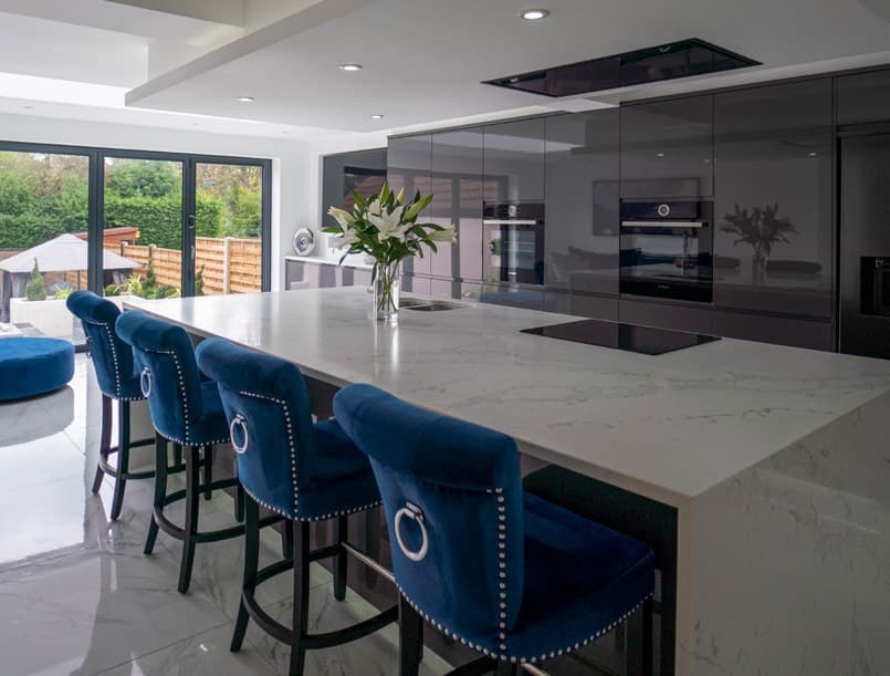 Large island with a white worktop and blue velvet stools