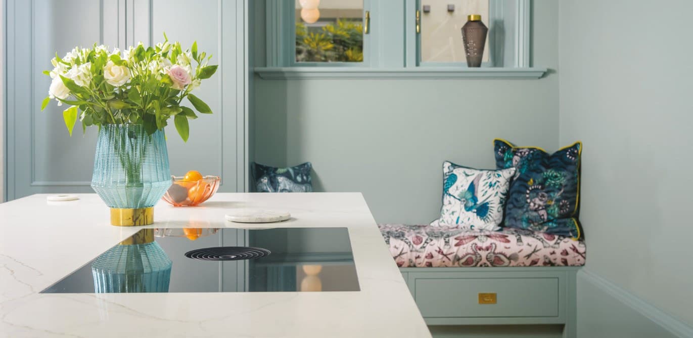 White worktop with an inset hob in a pale green kitchen